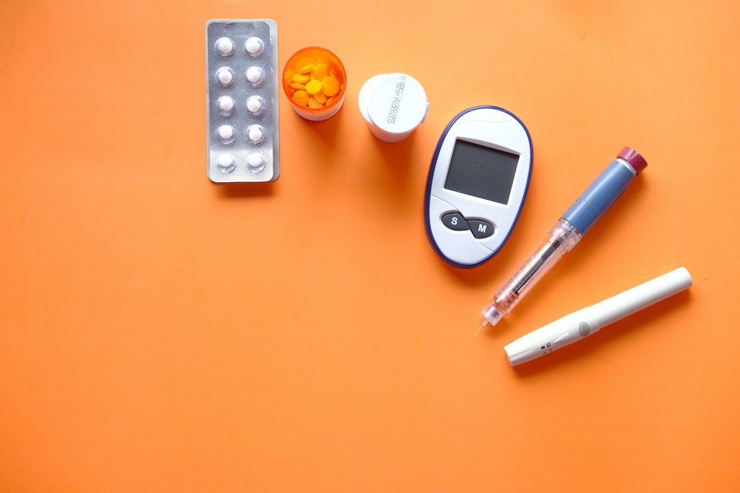 Diabetes testing supplies, an insulin pen, and pills on an orange background