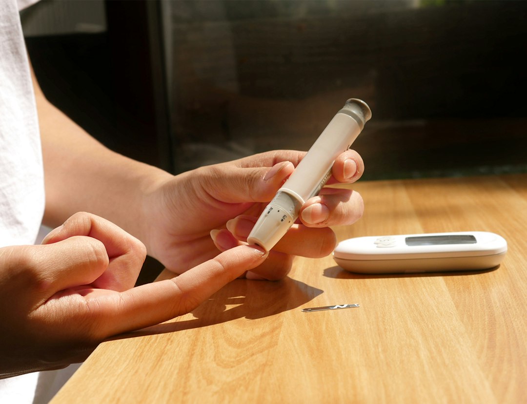 Person reviewing health information on a smartphone beside a glucose-monitoring device